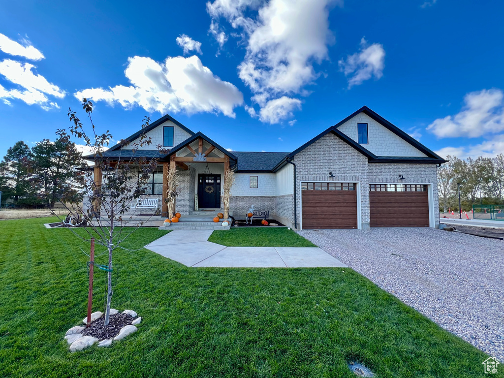 View of front of house with a porch, a front lawn, and a garage