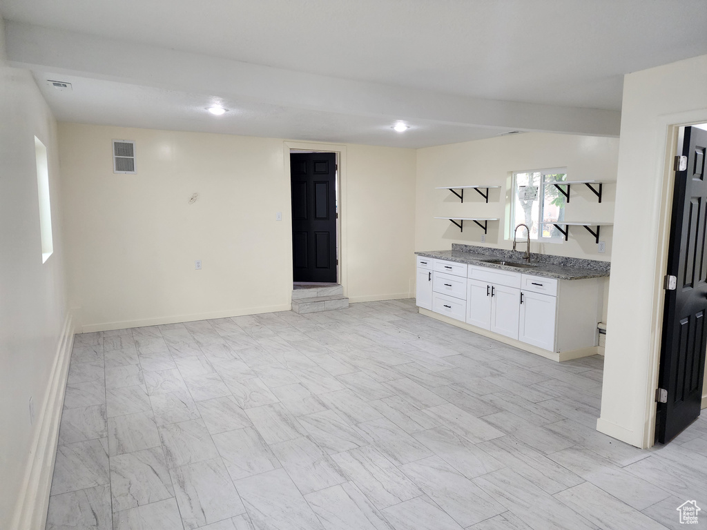 Interior space featuring light stone countertops, sink, and white cabinets