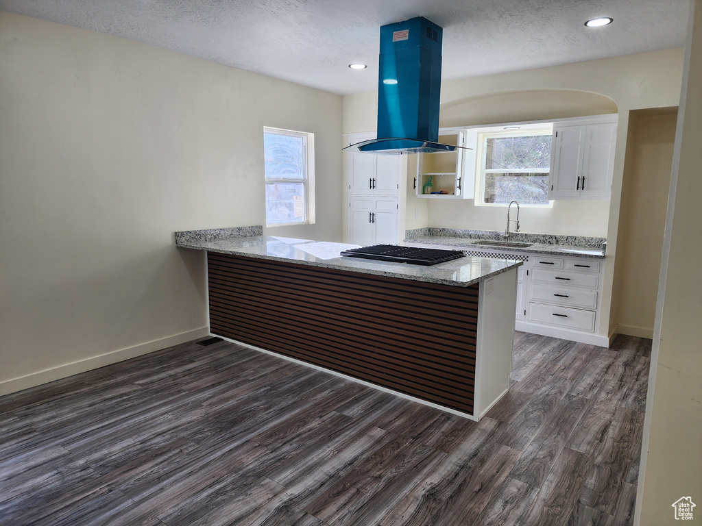 Kitchen with island exhaust hood, white cabinetry, dark hardwood / wood-style flooring, sink, and kitchen peninsula