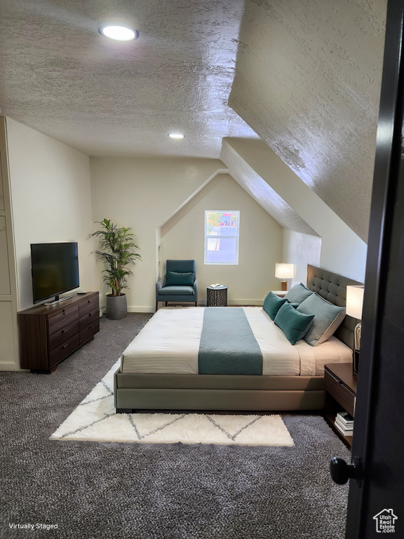 Carpeted bedroom with a textured ceiling and vaulted ceiling