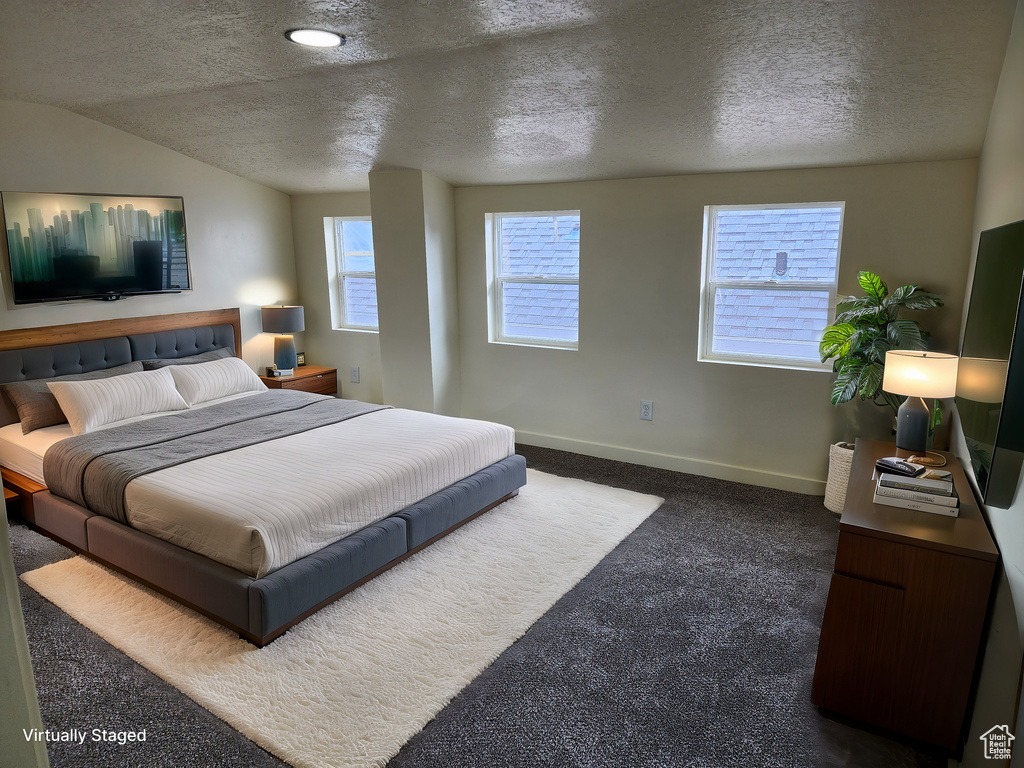 Bedroom featuring a textured ceiling, dark colored carpet, and vaulted ceiling