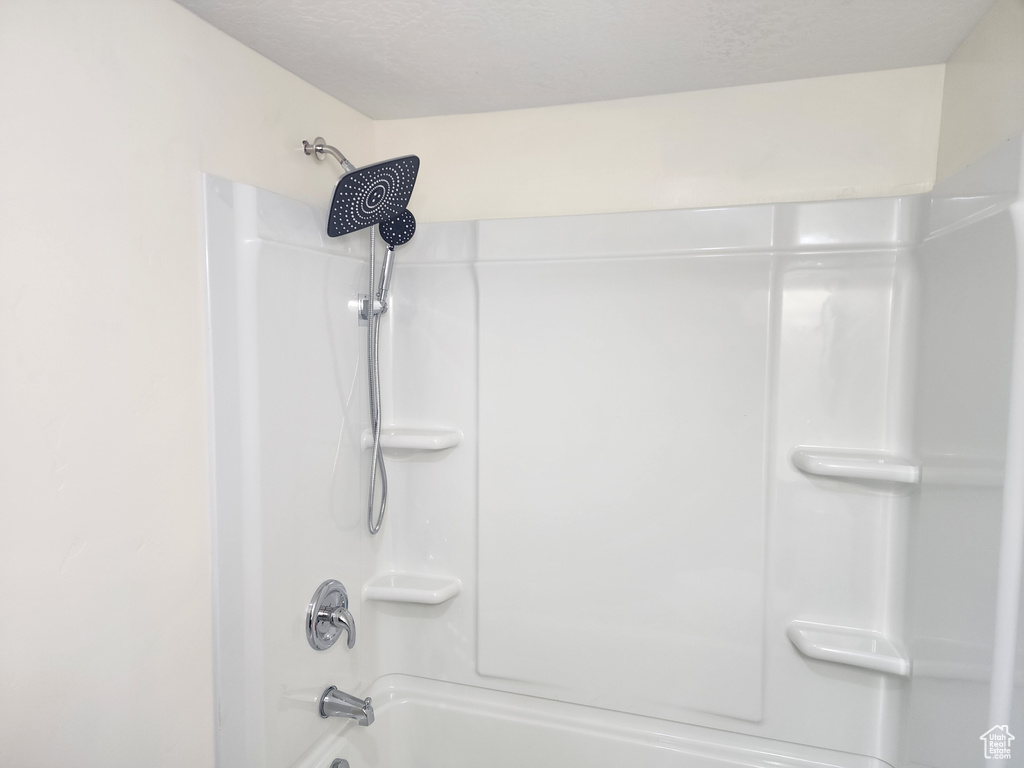 Bathroom with a textured ceiling and bathing tub / shower combination