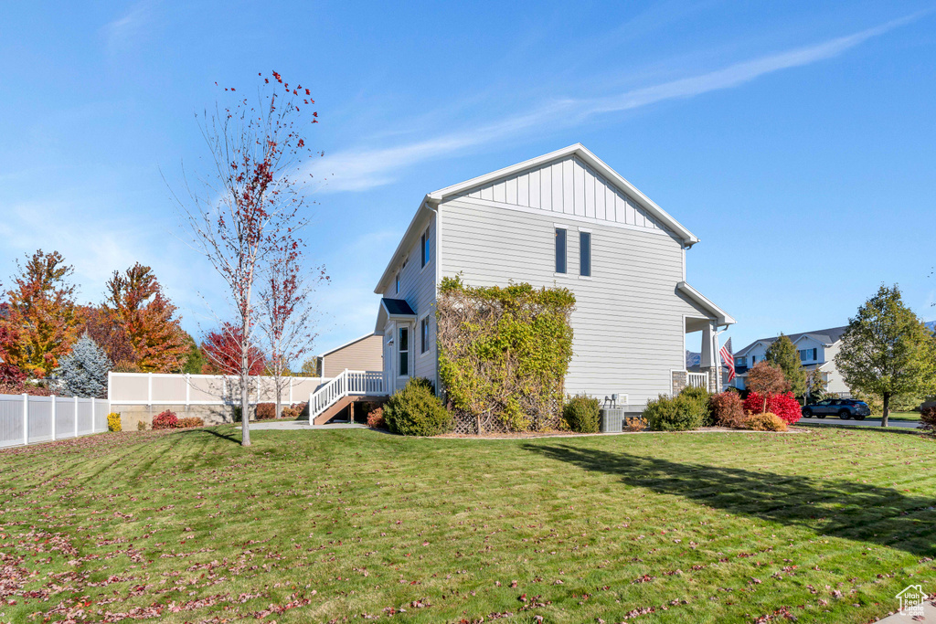 View of side of home featuring a lawn and central AC