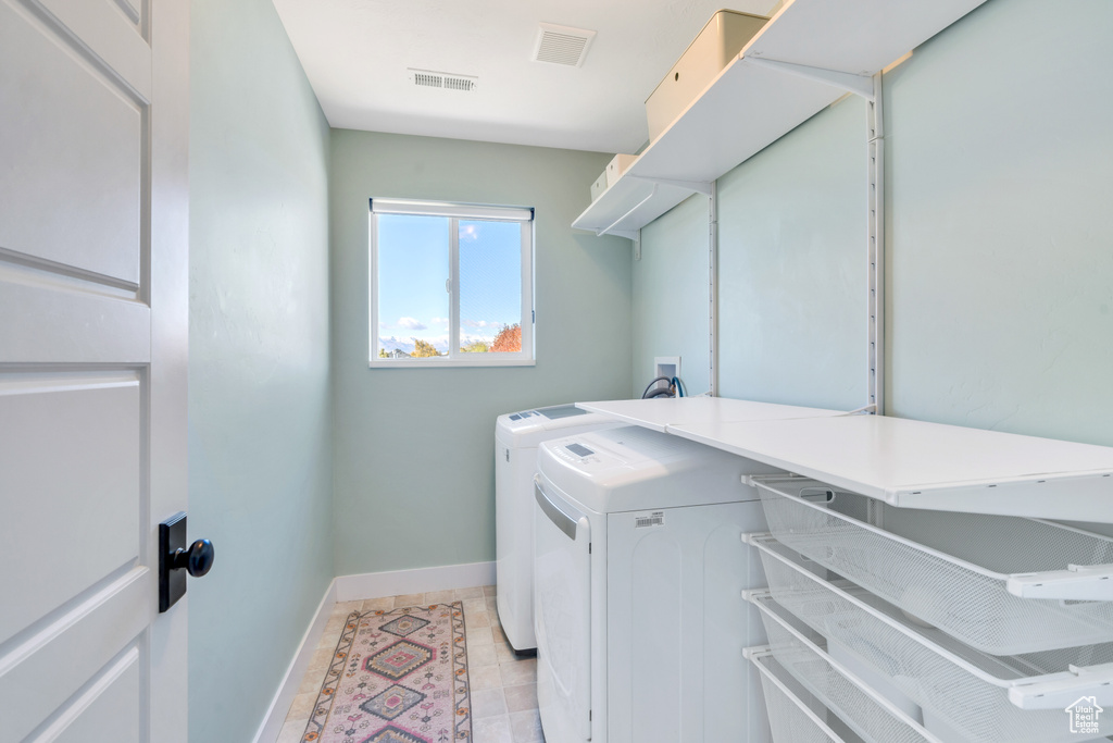 Clothes washing area with washing machine and clothes dryer and light tile patterned floors