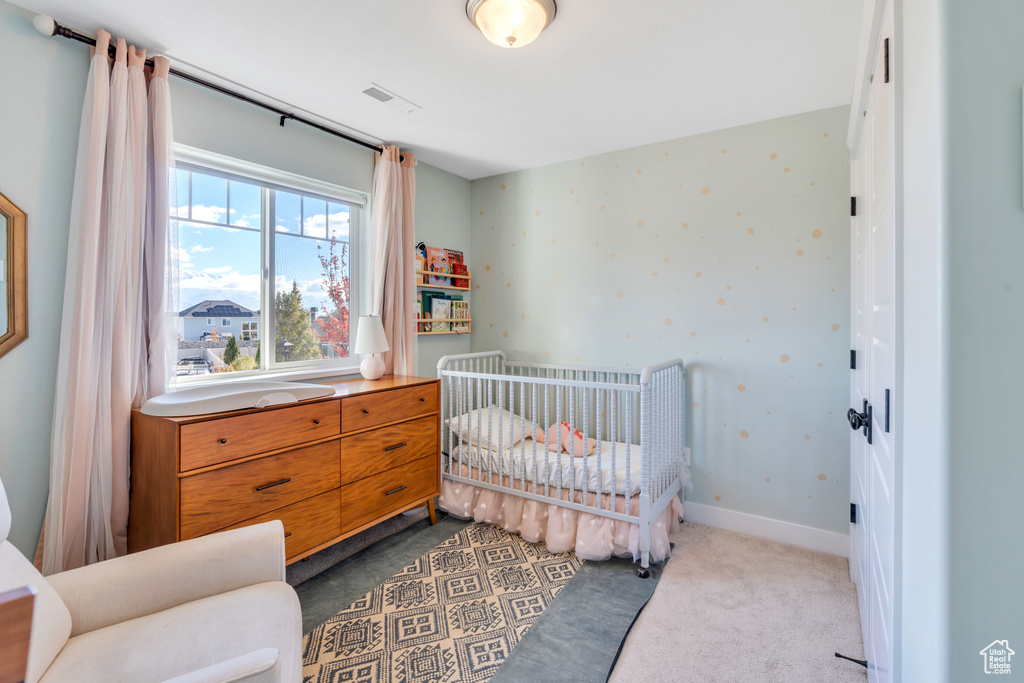 Bedroom featuring a nursery area and dark carpet