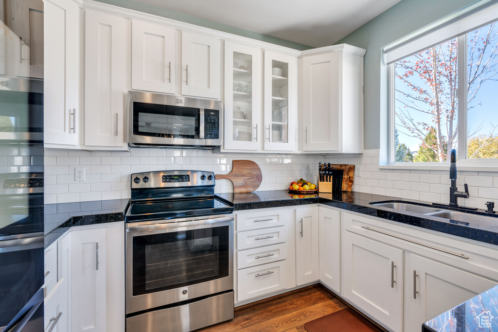 Kitchen featuring white cabinets, appliances with stainless steel finishes, sink, and dark stone countertops