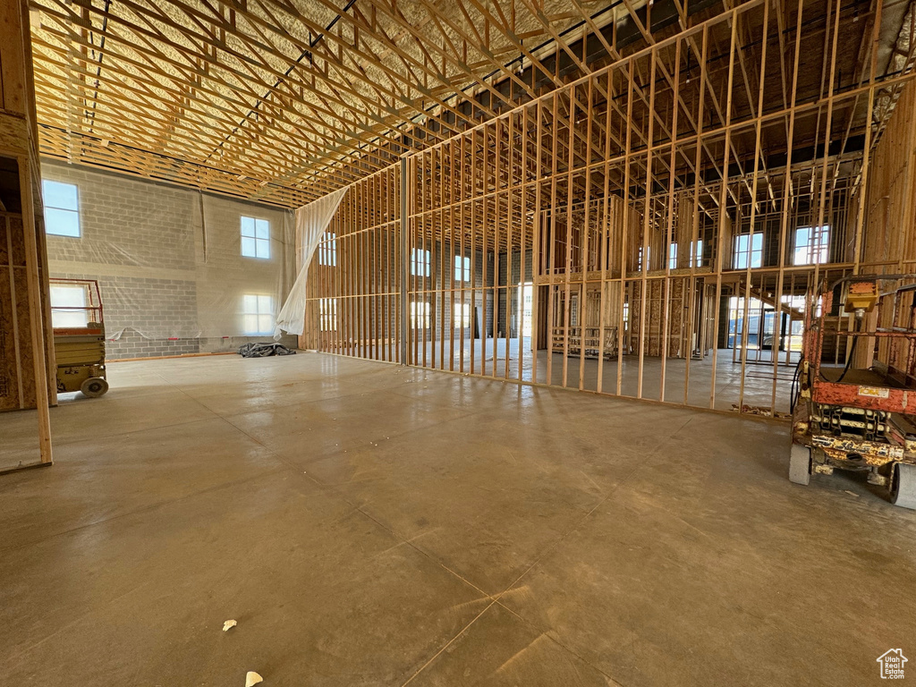 Miscellaneous room with a high ceiling, concrete flooring, and brick wall