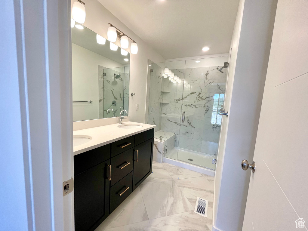 Bathroom featuring marble finish flooring, a marble finish shower, double vanity, and recessed lighting