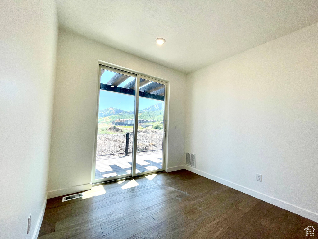Spare room with baseboards and dark wood-style floors