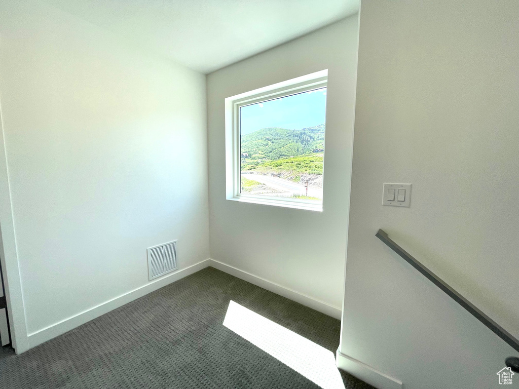 Empty room with baseboards and dark colored carpet