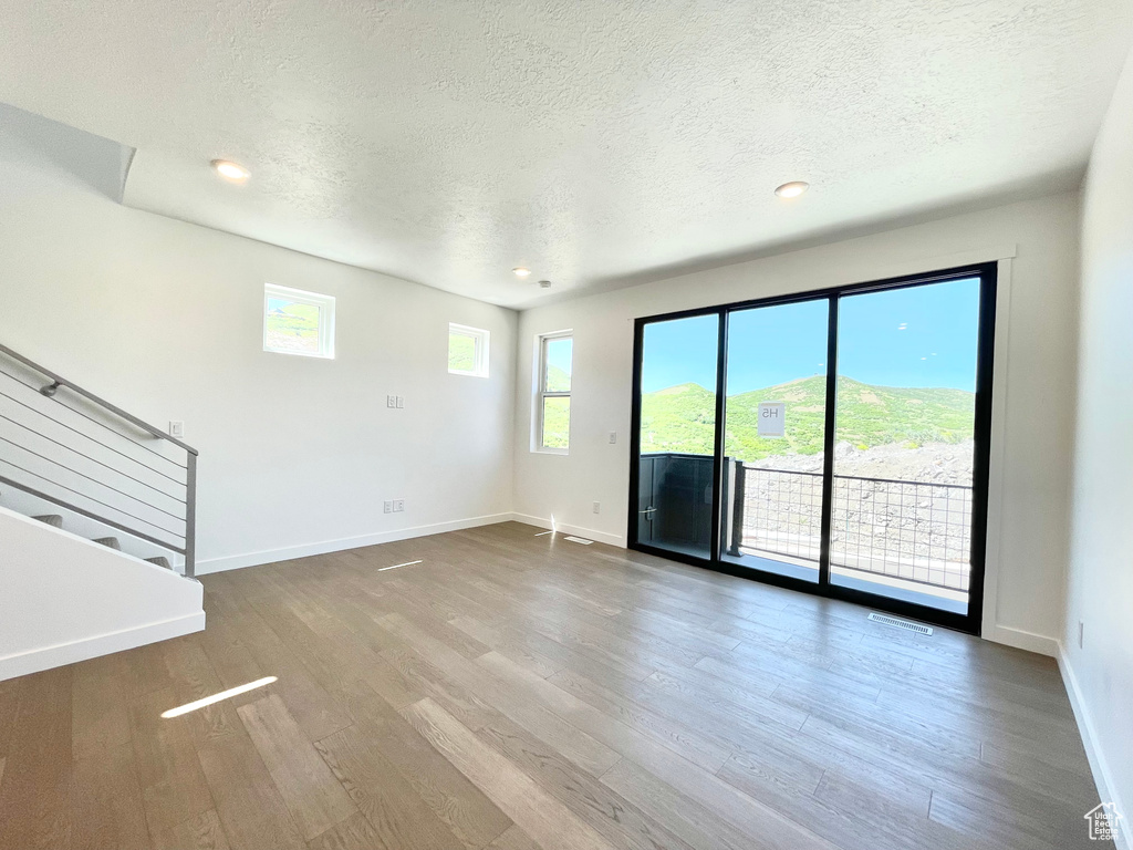 Unfurnished living room featuring a textured ceiling, wood finished floors, stairway, and recessed lighting