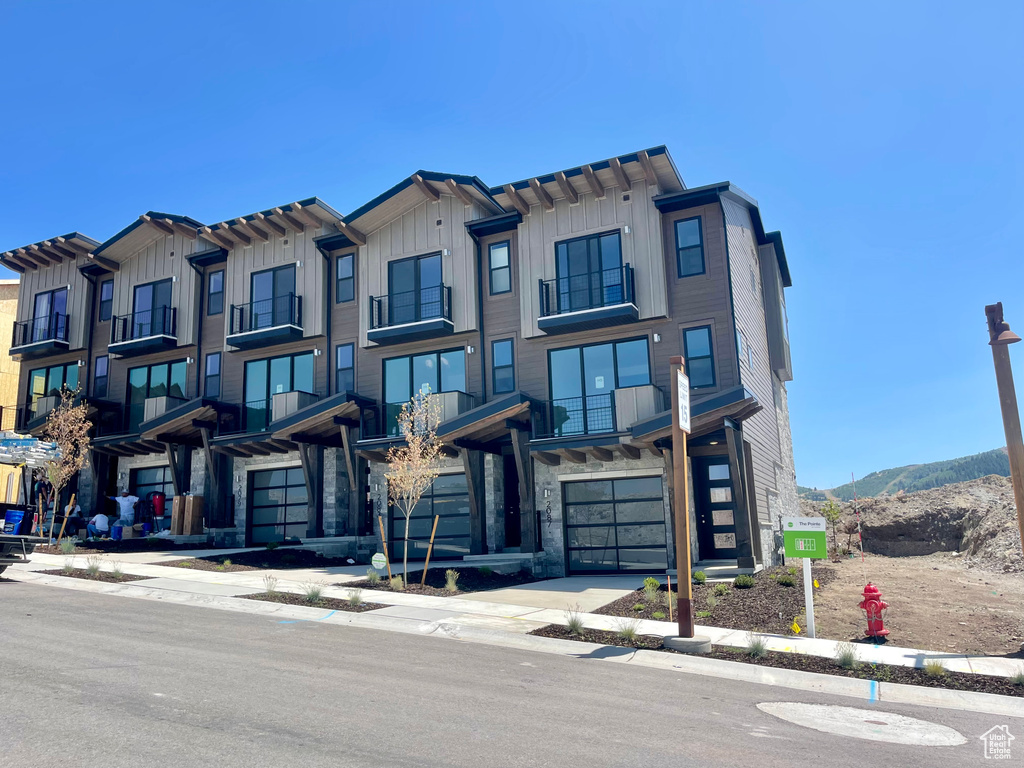 Townhome / multi-family property featuring board and batten siding, stone siding, an attached garage, and a mountain view