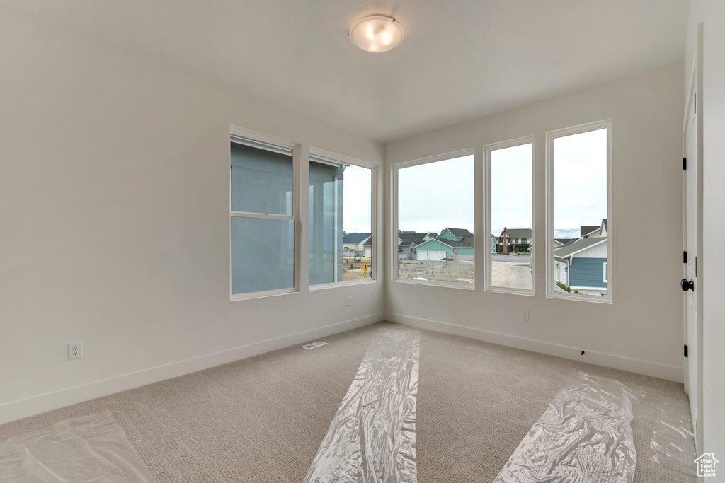 Unfurnished room featuring baseboards, a wealth of natural light, and light carpet