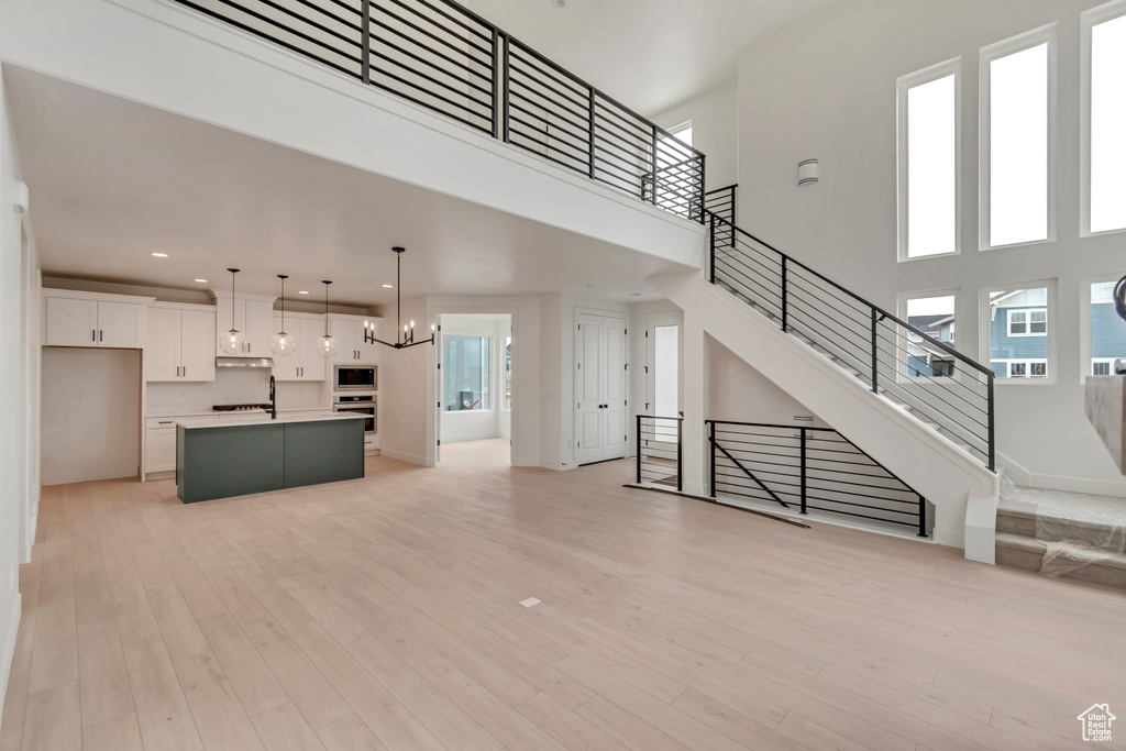 Unfurnished living room with recessed lighting, stairway, an inviting chandelier, and light wood finished floors