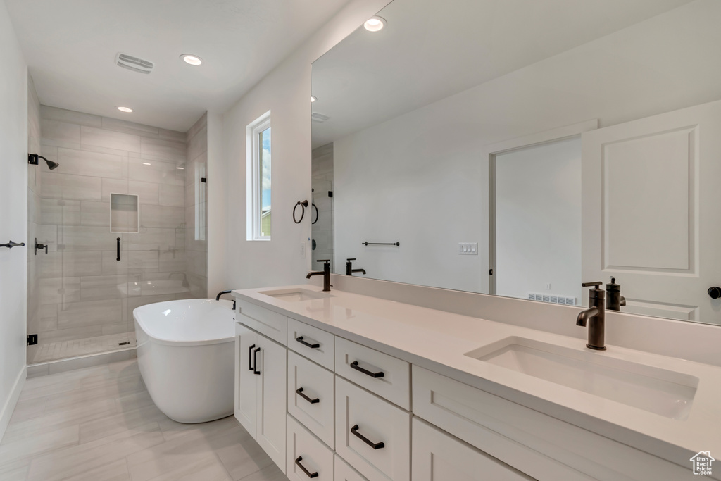 Full bath featuring a sink, a freestanding tub, a stall shower, and double vanity