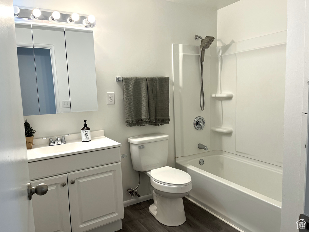 Full bathroom featuring vanity, shower / bath combination, toilet, baseboards, and wood finished floors