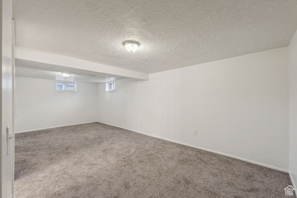 Basement featuring a textured ceiling and carpet floors