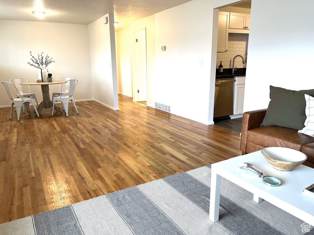 Living area featuring baseboards, a textured ceiling, visible vents, and wood finished floors