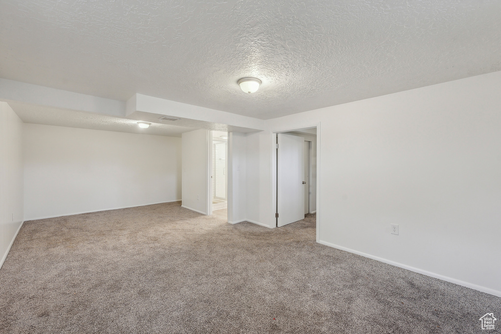 Carpeted empty room featuring a textured ceiling