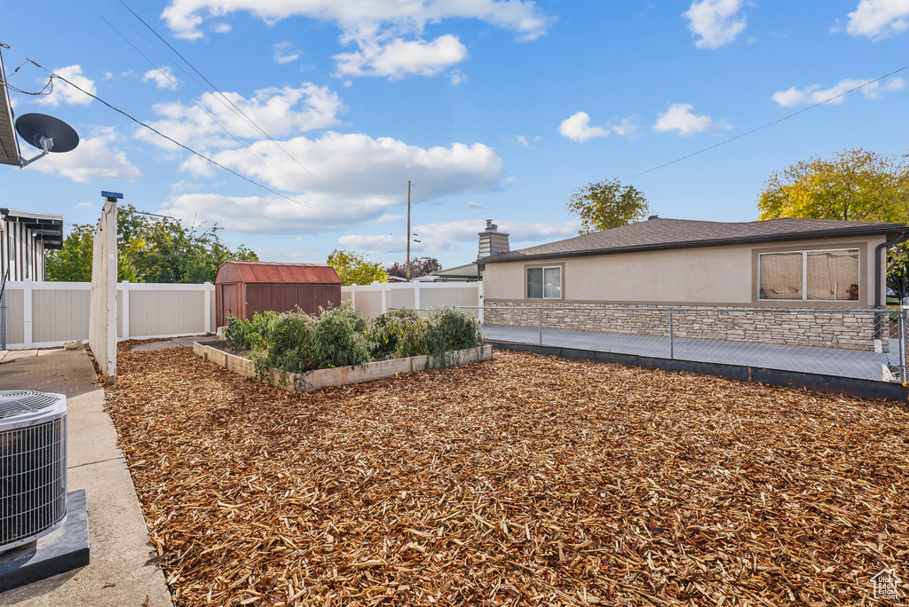 View of yard featuring a patio area, cooling unit, and a storage shed