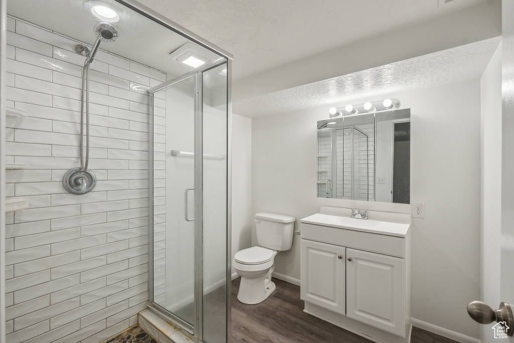 Bathroom with walk in shower, vanity, hardwood / wood-style floors, and toilet