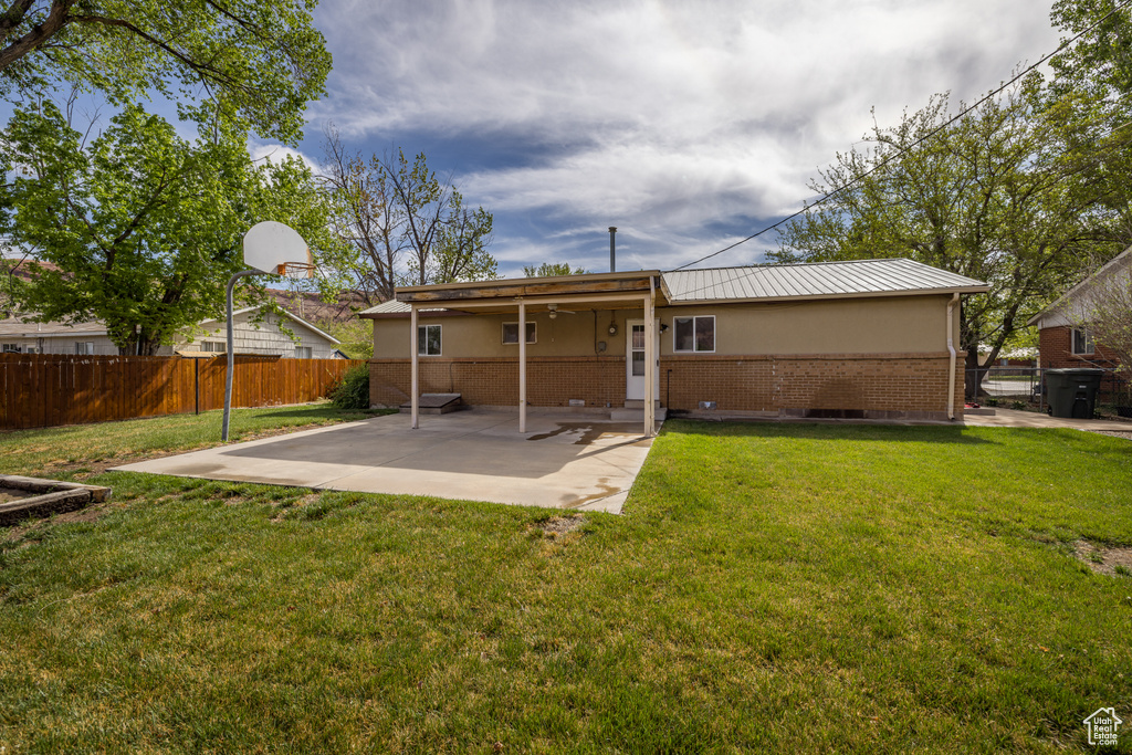 Back of property with a patio area, fence, a yard, metal roof, and brick siding
