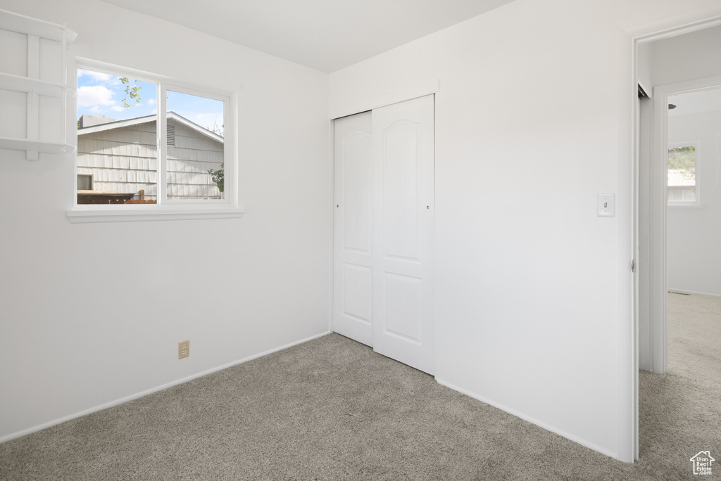 Unfurnished bedroom with carpet floors, a closet, baseboards, and multiple windows