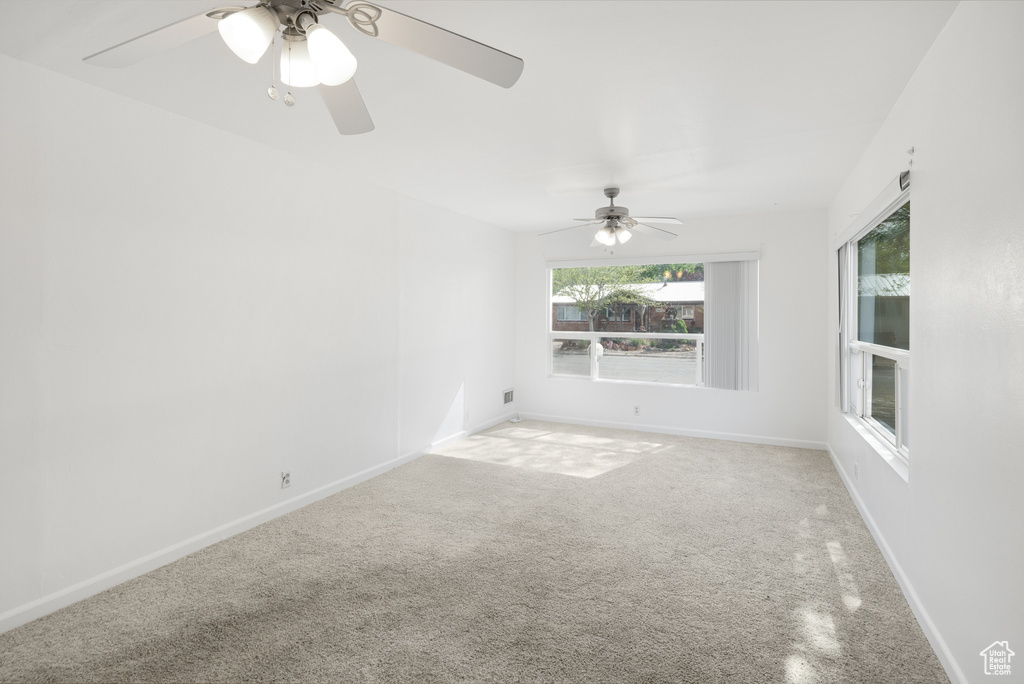 Empty room with carpet floors, a ceiling fan, and baseboards