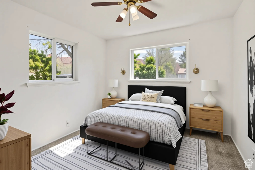 Bedroom featuring light colored carpet, multiple windows, and a ceiling fan