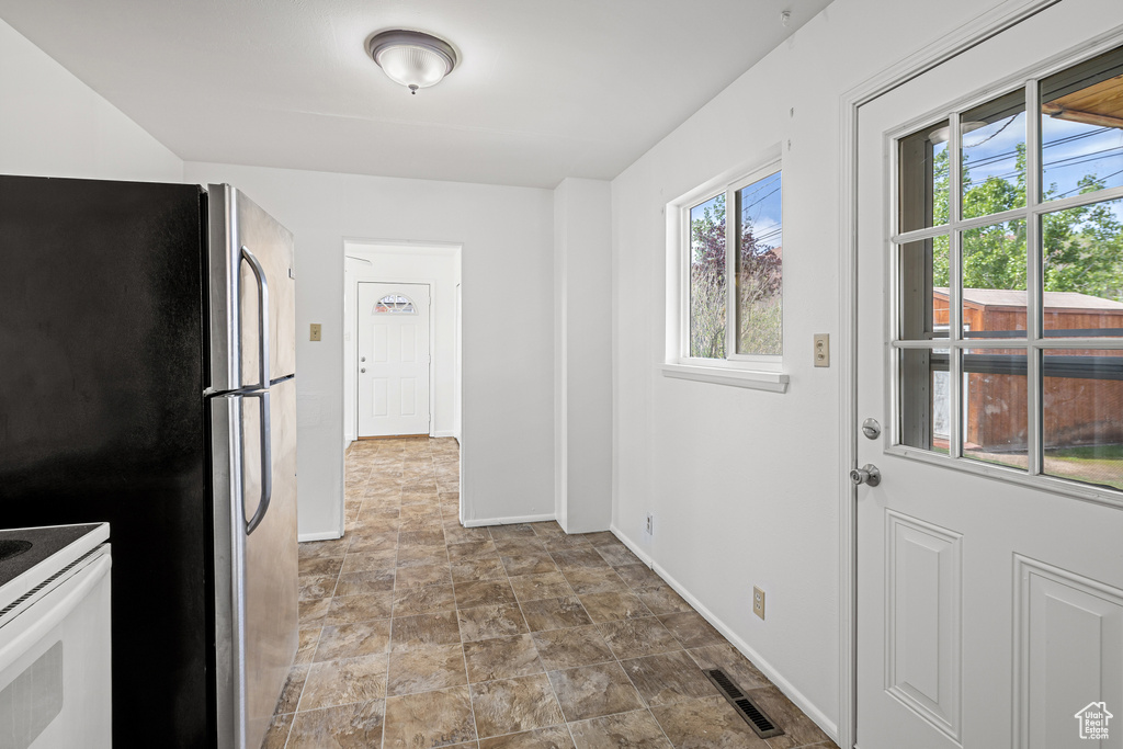 Kitchen featuring stone finish flooring, visible vents, freestanding refrigerator, baseboards, and white electric range