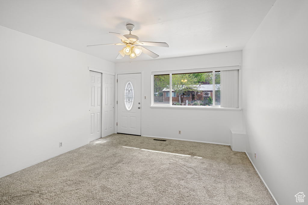 Entrance foyer with visible vents, a ceiling fan, and carpet flooring