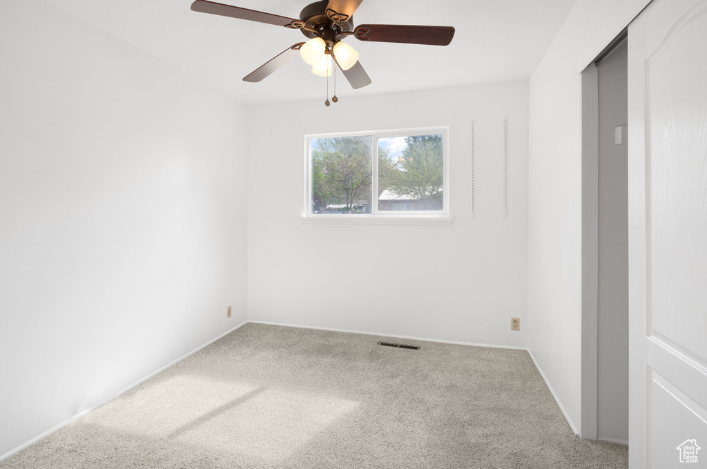 Unfurnished room featuring baseboards, a ceiling fan, visible vents, and carpet floors