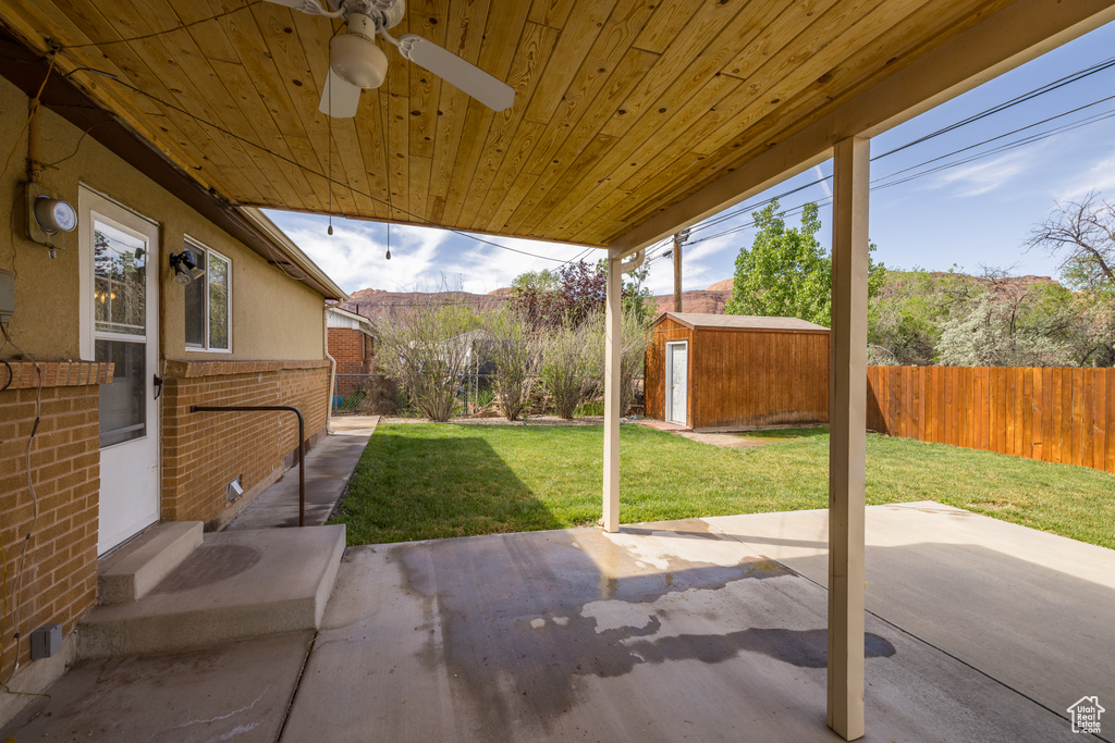 View of patio / terrace featuring a fenced backyard, a ceiling fan, an outdoor structure, and a storage unit