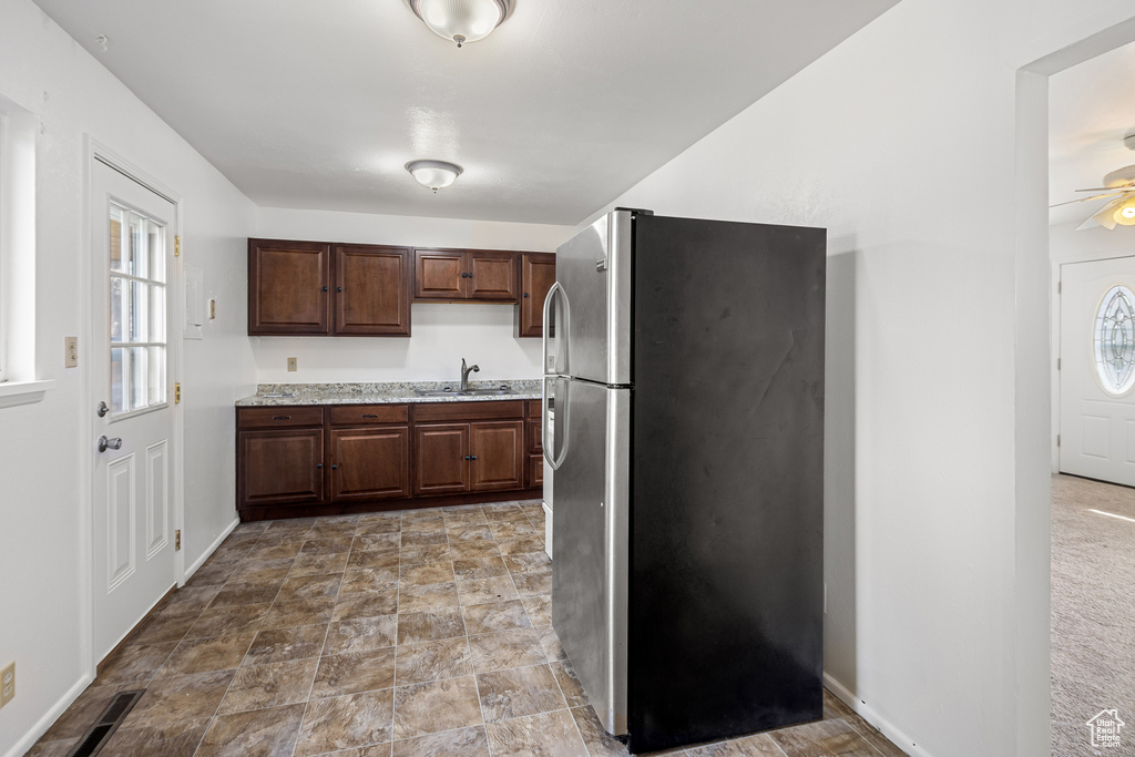 Kitchen with a sink, light countertops, ceiling fan, baseboards, and freestanding refrigerator