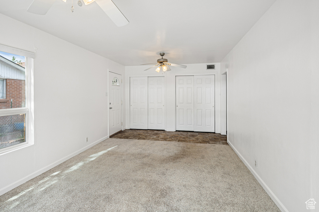 Unfurnished bedroom with carpet, multiple closets, and baseboards