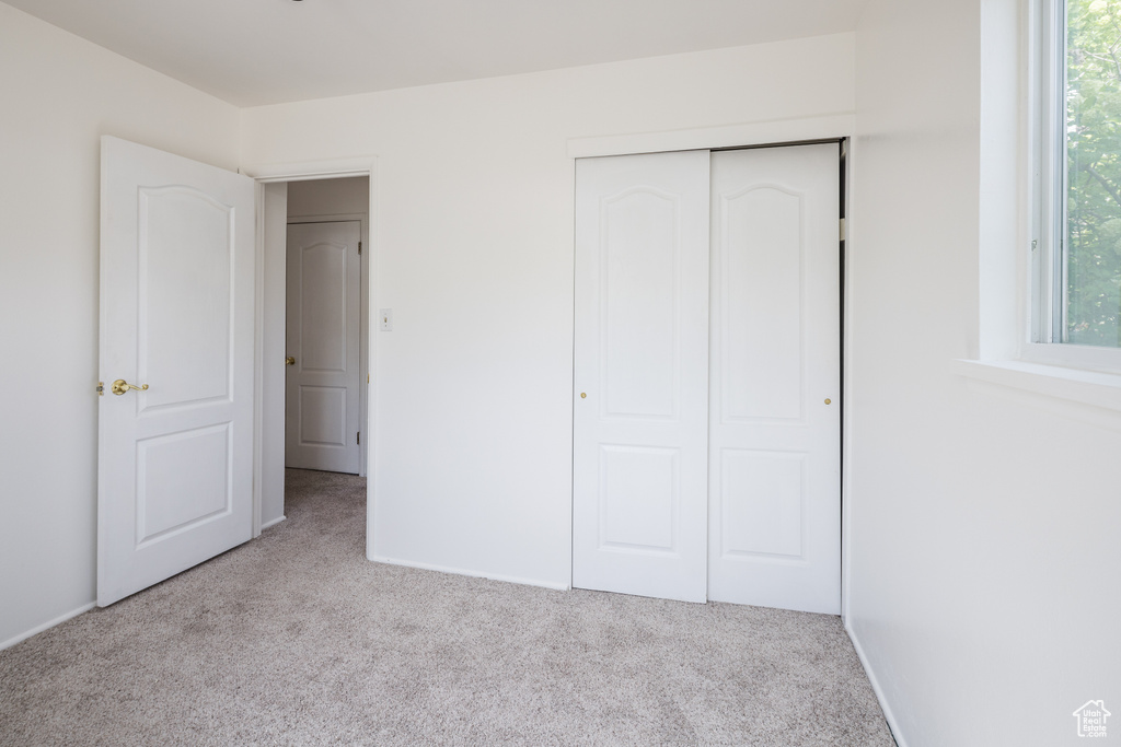 Unfurnished bedroom featuring baseboards, carpet flooring, and a closet