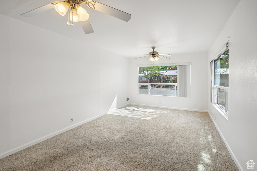 Unfurnished room with light colored carpet, a ceiling fan, and baseboards