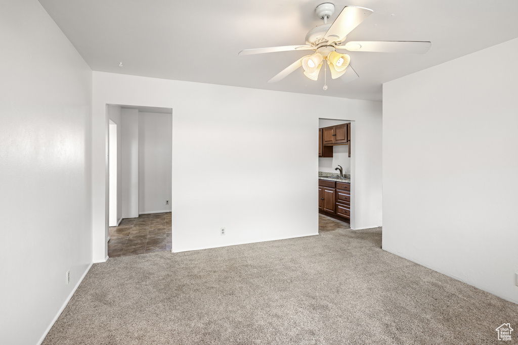 Spare room with a ceiling fan, carpet floors, and a sink