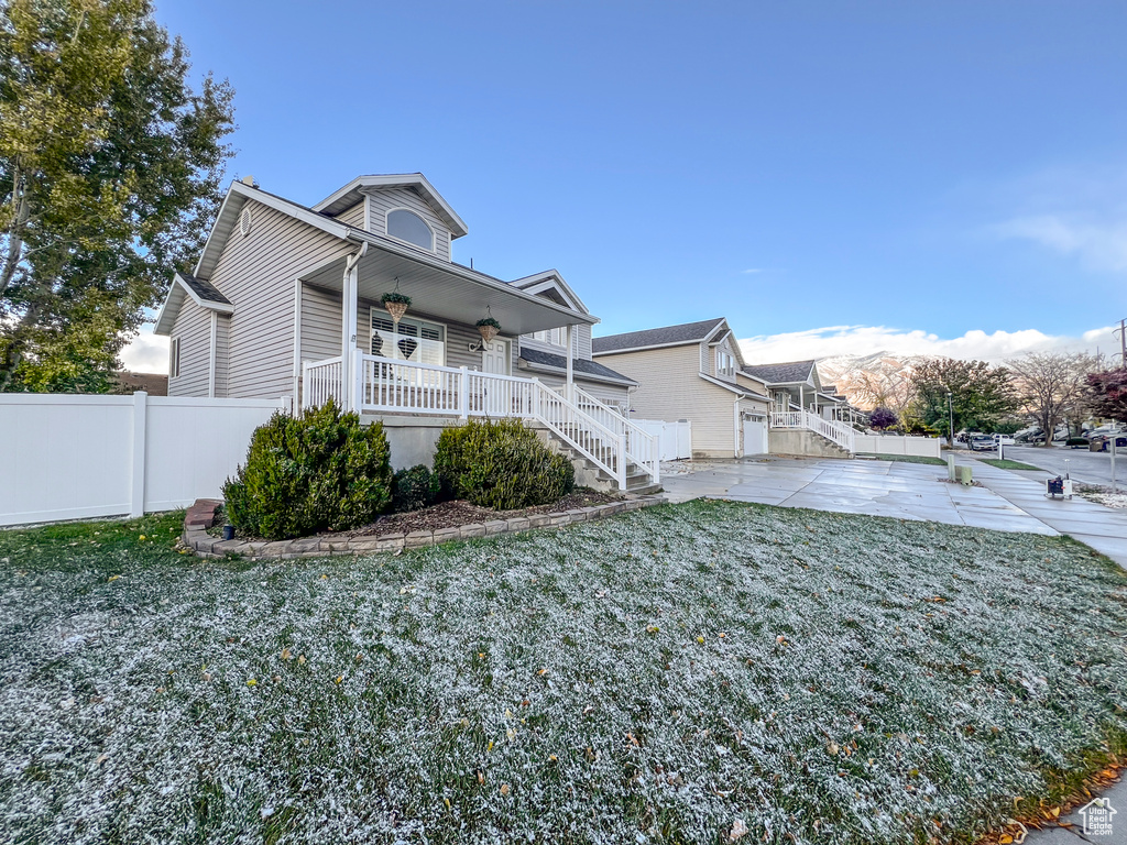 View of side of home featuring a porch, a lawn, and a mountain view