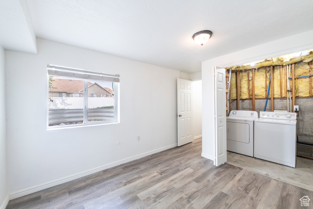 Clothes washing area with light hardwood / wood-style flooring and independent washer and dryer