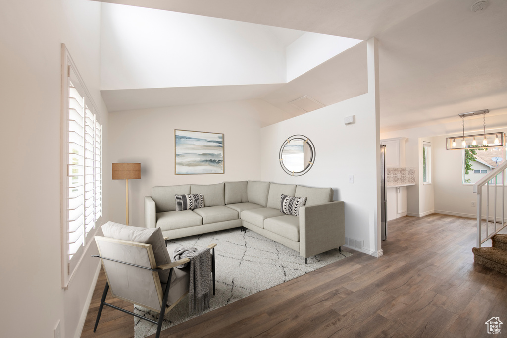 Living room with hardwood / wood-style flooring, vaulted ceiling, and an inviting chandelier