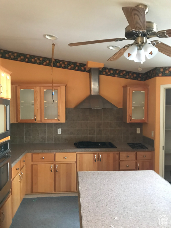 Kitchen with tasteful backsplash, wall chimney range hood, and oven