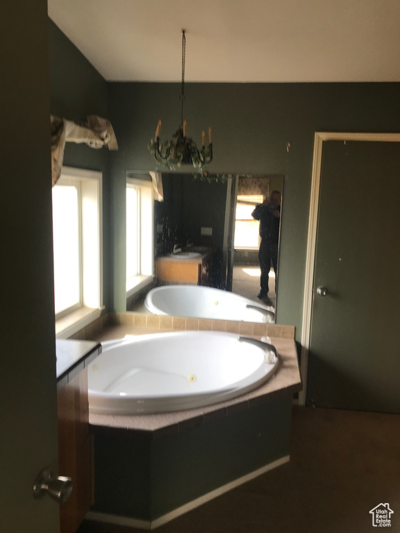 Bathroom featuring tiled bath and a chandelier