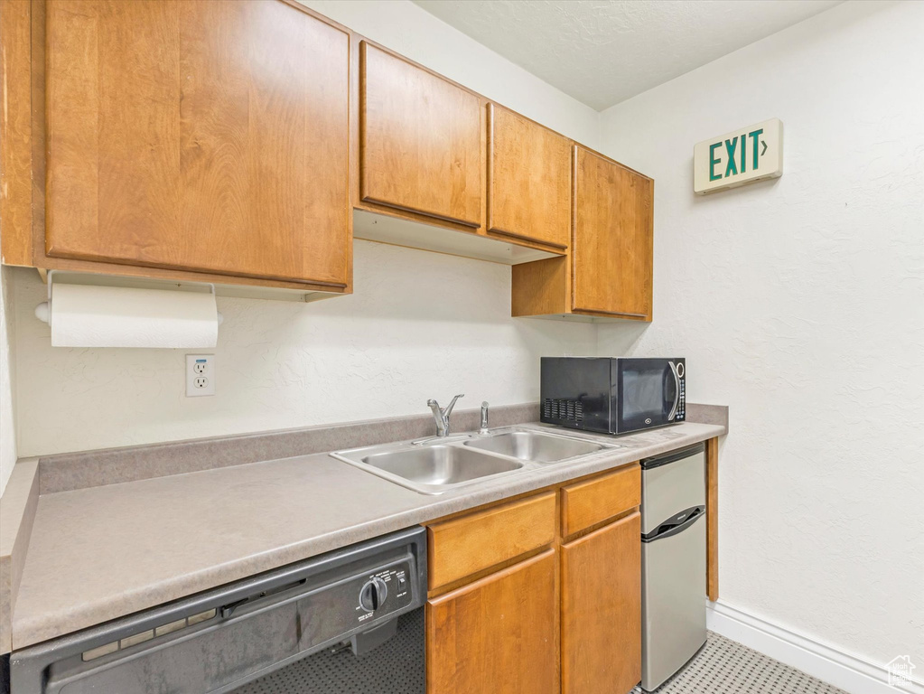 Kitchen with black appliances, sink, and light tile patterned floors