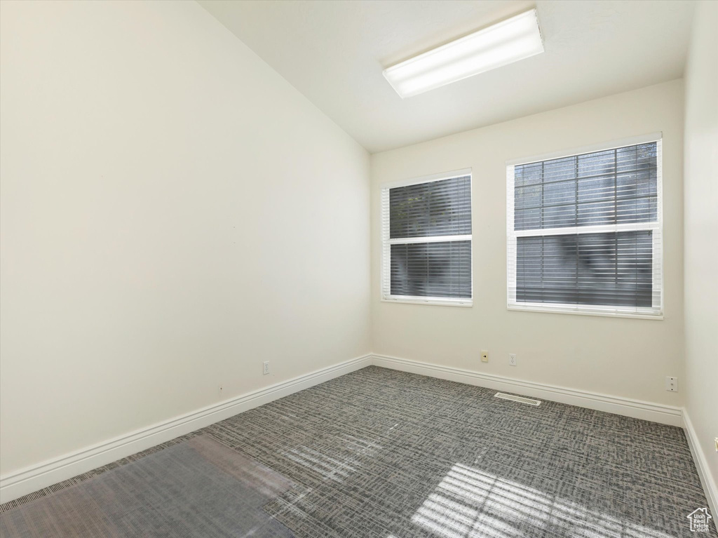 Unfurnished room featuring lofted ceiling and carpet