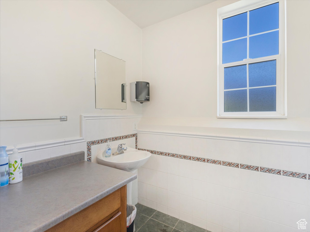 Bathroom featuring tile patterned flooring, vanity, and tile walls