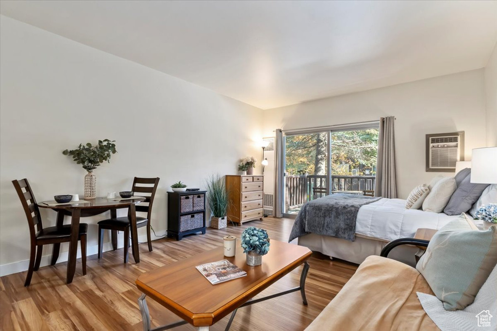 Bedroom with access to outside, wood-type flooring, and an AC wall unit