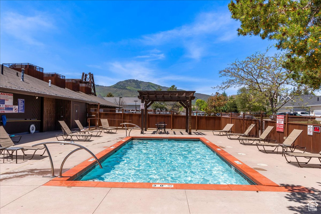 View of swimming pool with a patio area, a pergola, and a mountain view