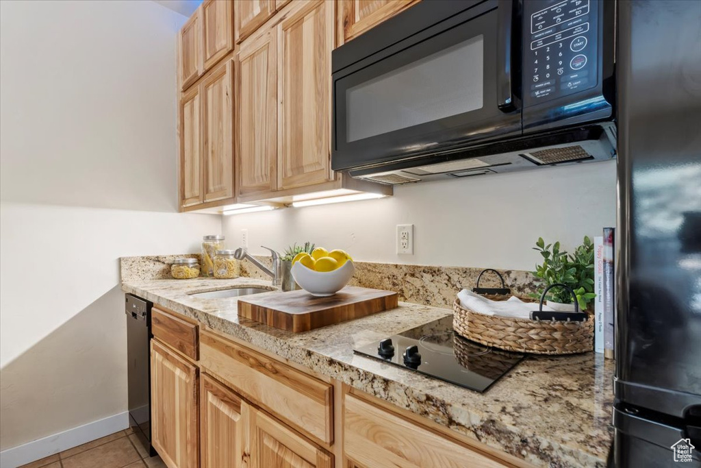 Kitchen featuring black appliances, light brown cabinetry, sink, and light tile patterned floors