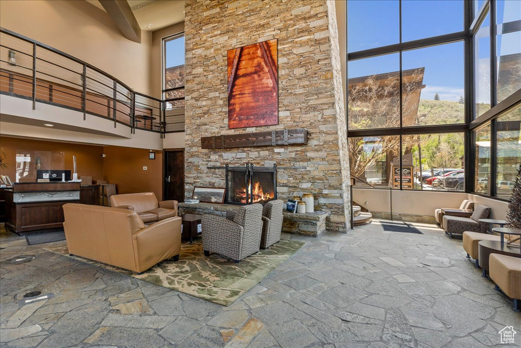 Living room with a towering ceiling, a stone fireplace, and plenty of natural light